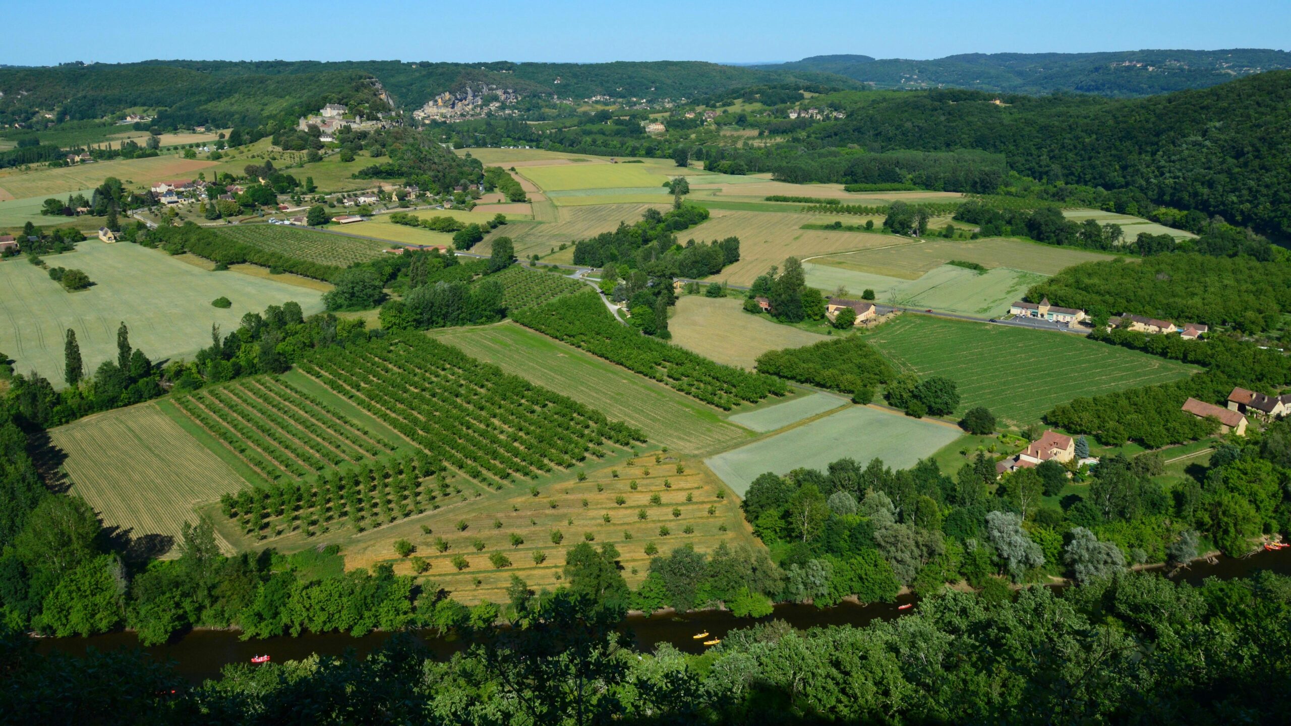 A stunning aerial view of lush countryside fields and farms under a bright summer sky.